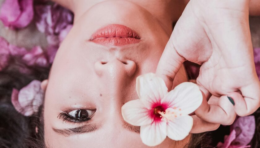 Elegant photoshoot featuring a woman holding a pink flower amidst petals.